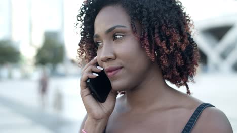 Cheerful-curly-woman-talking-with-interlocutor-through-phone